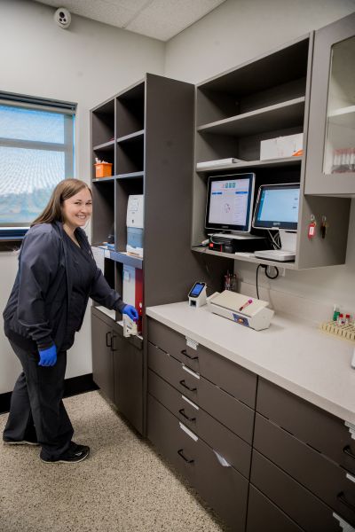 A woman in a lab coat stands in front of a desk